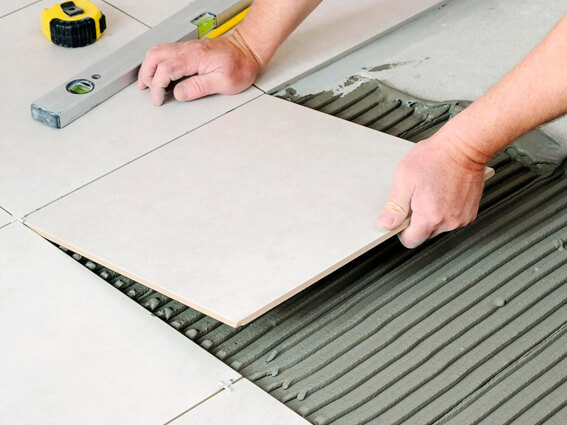 Image of tiles being laid on top of CI++ Matting using adhesive